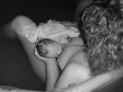 Mother breastfeeding newborn after giving homebirth